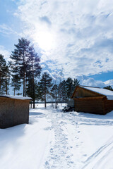 winter landscape with wooden houses and a snowmobile. bright sunny day. vertical photo