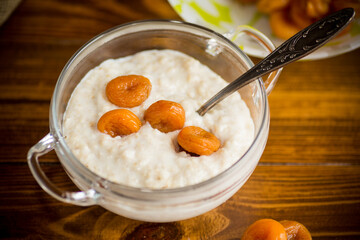 cooked boiled sweet oatmeal with dried apricots in a bowl