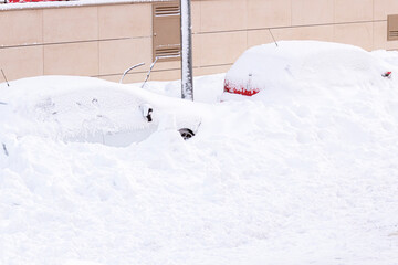 A group of modern cars covered in the snow parked outdoors in winter