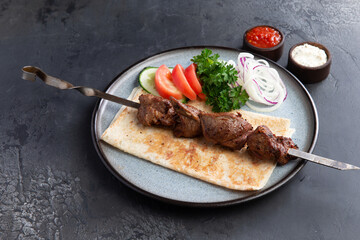Lamb shashlik on a skewer in a plate.