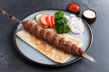 Kebab on a skewer in a plate.