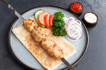 Chicken kebab on a skewer in a plate.