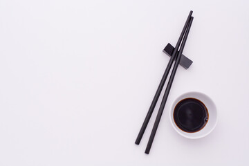 chopsticks and bowl with soya sauce on a white board with empty space