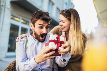 The young man gives a gift to a young girl in the cafe