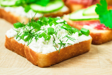 sandwich with soft cheese and herbs, wooden table, closeup