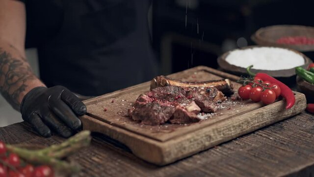 Chef cook spinkle black pepper on the meat. Slowmotion.