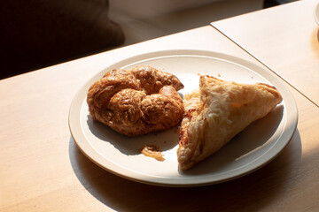Morning croissant and pie in white plate on wooden table