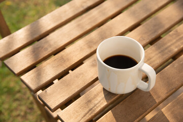 black coffee cup on wood table with green grasses morning light stock photo
