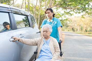 Help and support asian senior or elderly old lady woman patient sitting on wheelchair prepare get to her car : healthy strong medical concept.