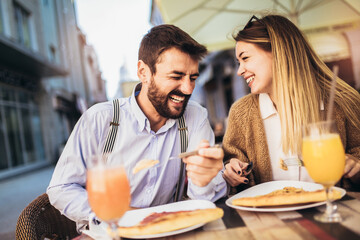 Young couple sitting in a restaurant eating pizza