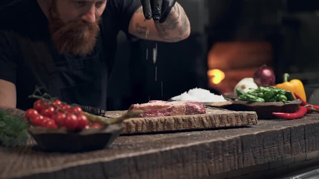 Chef cook spinkle salt on the piece of raw meat. Slowmotion.