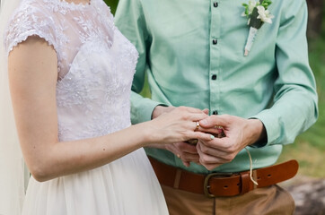 Obraz na płótnie Canvas The bride and groom exchange wedding rings, wedding ceremony, hands close-up.