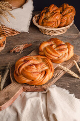 Fresh baked goods - delicious wicker buns with cinnamon on a wooden