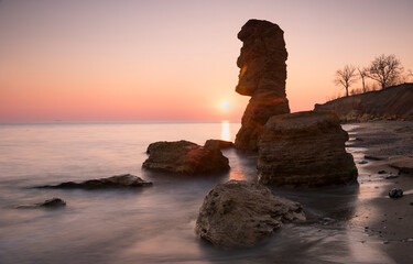 Big shell stone like idol, sunrise behind and sunny path to the sea. Long exposure