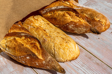 French traditional baguettes in paper bags on wooden table background.