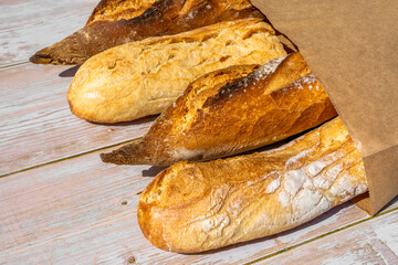 French traditional baguettes in paper bags on wooden table background.