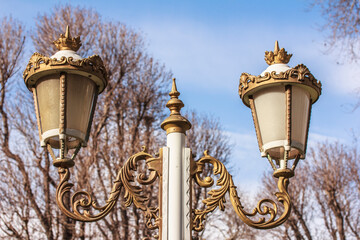 Fototapeta na wymiar Royal style street lights against blue sky . Old white decorative lantern. Lights, lighting, lamp, lantern. Stock photo, copy space, close up
