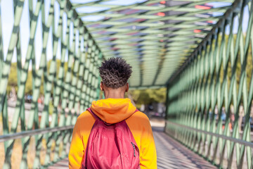 Back view of an afro style boy walking inside a metal bridge