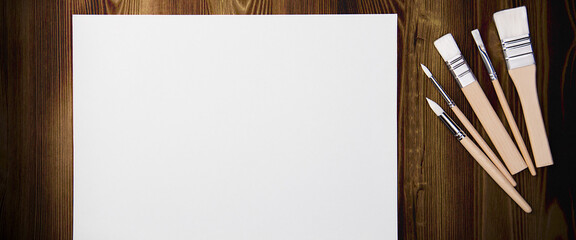 A clean white sheet and brushes on a wood textured background with space to copy.