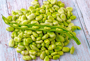 Broad beans in their open pod on a group of fresh beans just extracted from their pod