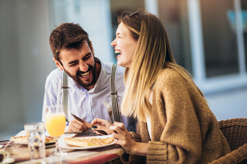 Young couple sitting in a restaurant eating pizza
