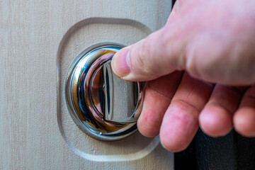 Close-up of a human hand on a round door latch.
