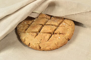A round loaf of homemade bread covered with a piece of coarse canvas