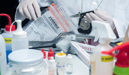 Fototapeta premium police scientist extracts knife from evidence bag in crime lab, conceptual image
