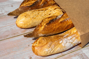 French traditional baguettes in paper bags on wooden table background.