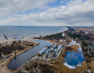 Fototapeta na wymiar Aerial view of Sventoji resort on the coastline of Baltic sea in Lithuania. City panorama with port and new residential area in it