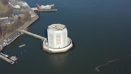 an aerial view of the Governors Island ventilation structure for the Brooklyn Battery Tunnel. The camera truck right and pan left over the structure in New York Harbor on a calm and sunny day.