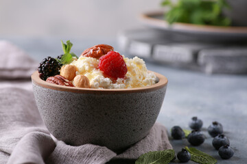 Healthy breakfast. Rustic cottage cheese in a gray bowl with berries and honey, nuts and mint on a gray table. Background image, copy space, horizontal