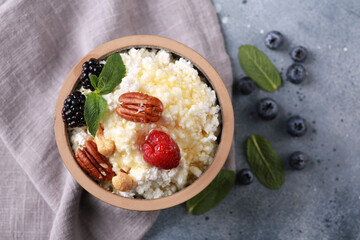 Healthy breakfast. Rustic cottage cheese in a gray bowl with berries and honey, nuts and mint on a gray table. Background image, copy space, horizontal