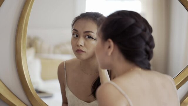 Beautiful woman looking into the mirror and applying mascara