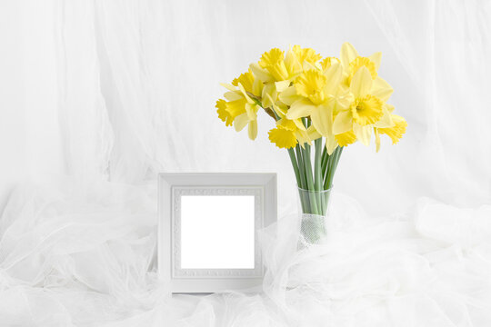 composition of spring bouquet flowers and a photo frame in white. layout for invitation, postcard mock-up