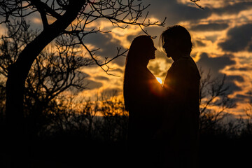 Naklejka na ściany i meble Silhouette of romantic couple in love, man and women in sunset sky. Romantic of relationships between couple love in the garden