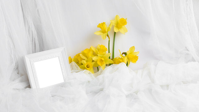 floral banner with place for text. composition of spring flowers and a photo frame in white. layout for invitation, postcard mock-up