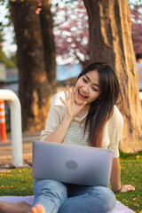 Portrait picture of A beautiful woman using a laptop, video call, spent holiday time in park. Holiday concept. Technology.