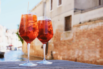 Two glasses of Spritz Veneziano cocktail served near the Venetian canal.  Popular italian summer aperitif drink. Copy space. Venice background.