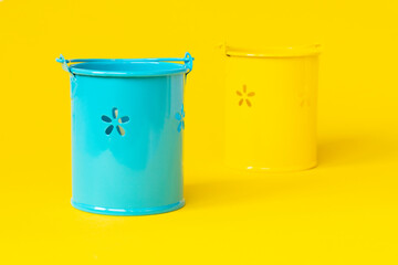 decorative yellow and blue buckets on a yellow background. Farming or repair concept. Small Buckets for planting flowers