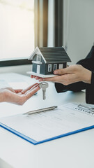 Hand a real estate agent hold the home model, and explain the business contract, rent, buy, mortgage, loan, or home insurance to the buyer woman