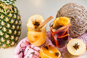 Mulled wine, grog and punch hot alcohol drinks on the table with seasonal decoration: pineapple,...