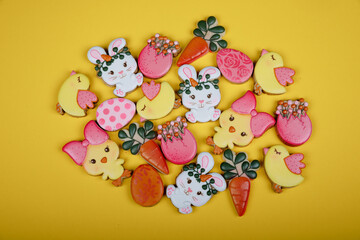 Closeup of variation of different Easter sugar cookies decorated with royal icing. Eggs, bunny, carrots and chicken on yellow background. Lovely sweet gift or postcard