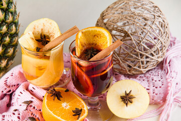 Mulled wine, grog and punch hot alcohol drinks on the table with seasonal decoration: pineapple,...