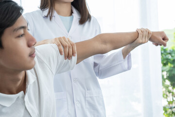 Female doctor doing physical therapy By extending the hand of a male patient