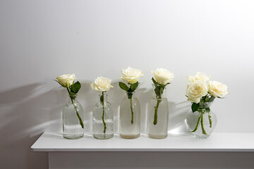 Bouquet of white roses in a glass figured vase on a white fireplace console.