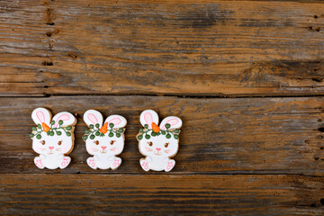 Closeup of variation of different Easter sugar cookies decorated with royal icing. Bunny rabbit with carrots on wooden background. Lovely sweet gift or postcard