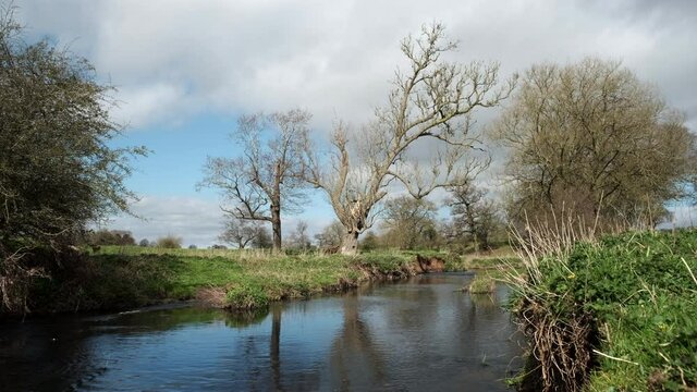 A sunny windy day on the river Arrow in Warwickshire, England as clouds roll over head.