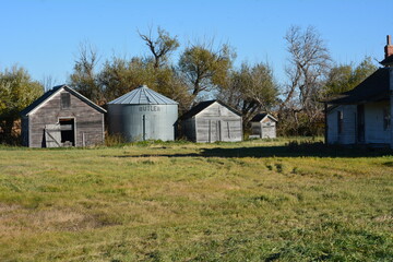 Obraz premium Grain bin storage next to old abandoned farm house