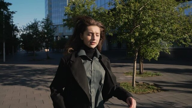 attractive young woman in a business suit and with a bag runs down the city street towards the camera. Slow motion. High quality FullHD footage